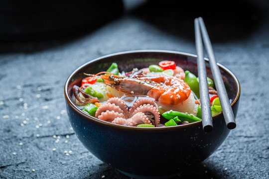Delicious seafood noodle in dark bowl with chopsticks