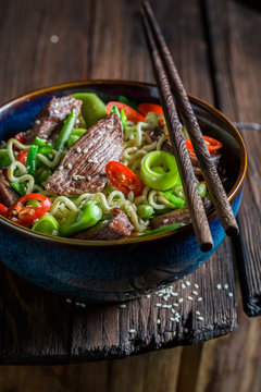 Closeup of hot noodle in dark bowl with chopsticks