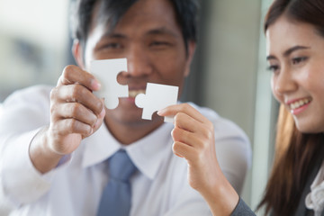 Male businessmen and business women, holding jigsaws together, represents a partnership team.