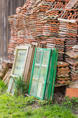 window frames leaning on stack of roof tiles