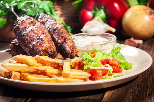 Grilled shish kebab served with fried chips and salad