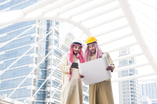 Engineers are carrying out construction plans, standing to speak with the construction worker in front of the construction site.