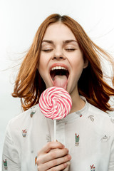 red-haired woman with closed eyes licks a big lollipop