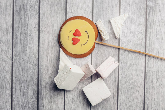 cookie smiley on a stick and marshmallow on a wooden background