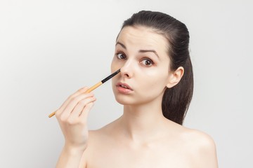 brunette with bare shoulders walking on the nose of a make-up brush...