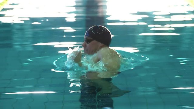 Male swimmer comes up to water surface in pool HD slow-motion video. Professional man athlete training swimming on water