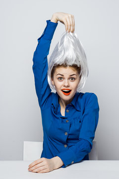 Surprised Woman In A Blue Shirt Trying On A Wig