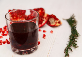 A glass of pomegranate juice and pomegranate seeds