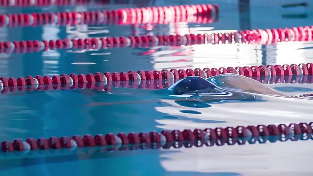 Male swimmer swims in pool HD slow-motion video. Front crawl freestyle training. Professional athlete on water lane. Side view