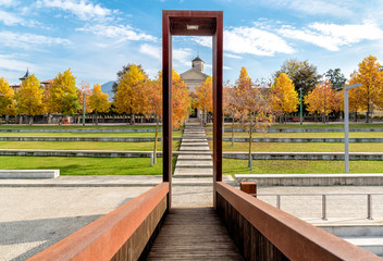 Autumn park of Luino with  view Ancient Sanctuary of Madonna of Carmine from bridge, Italy