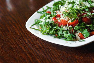 Fresh salad with tomato, ruccola on kitchen table.