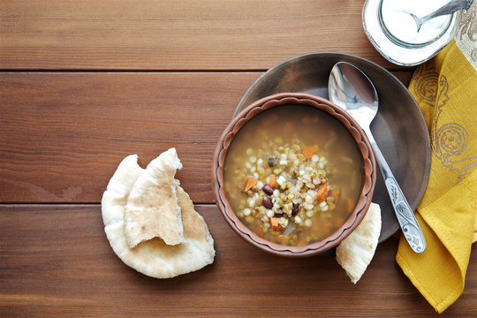 Soup with beans, lentils, peas and vegetables on wooden background. Top view, copy space