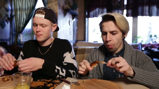 Hipsters eating delicious roasted chicken wings