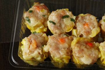 The pork dumpling in clear plastic tray packaging put on dark background scene.