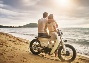 Obraz premium romantic couple sitting on vintage bike watching sunset at koh samui thailand
