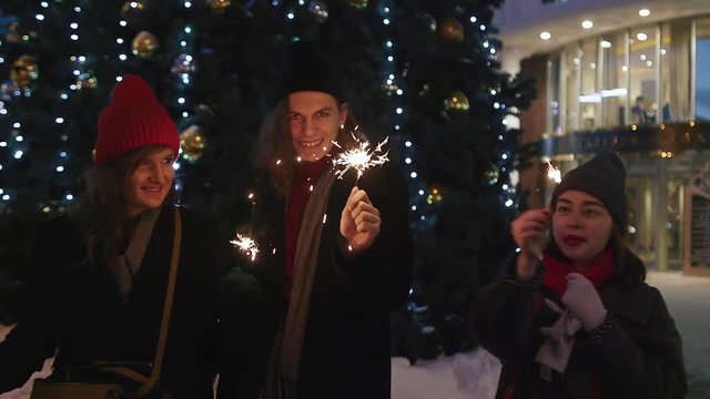 Group of friends having fun with sparklers. They hugs and smiles. Xmas party