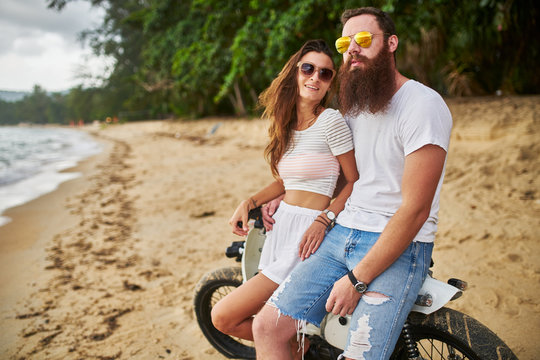 expat couple sitting on vintage bike on thai beach