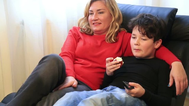Mother and her young boy having fun while watching tv at home