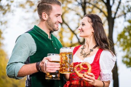 Bayer und Bayerin mit Bierkr&uuml;gen und Bretzeln im Herbst