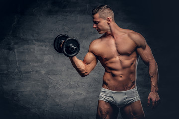 Fototapeta na wymiar Shirtless muscular male holds dumbbell on grey background.