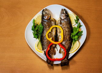 Two baked trouts on wooden background