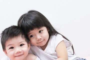 Baby Sister and Brother in White shirt Hugging each other.
