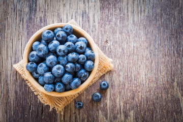 Blueberries in wooden bowl on wooden table background