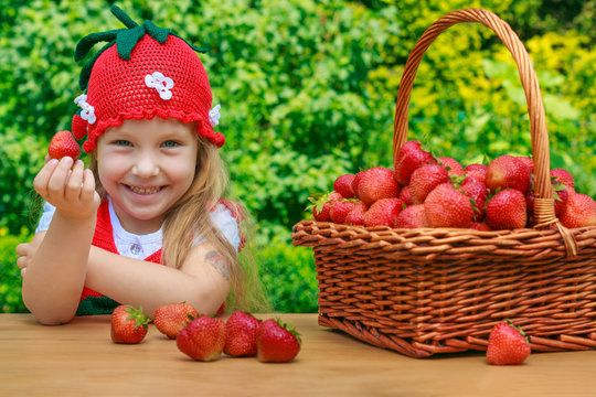 A funny little girl 4 years old with a basket of strawberries