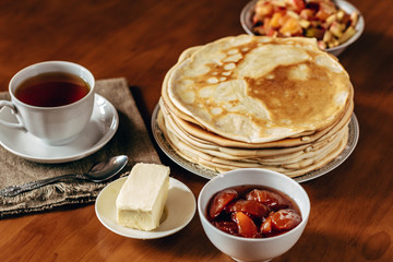 Stack of delicious homemade pancakes or blini with chocolate, cup of tea, butter