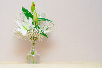 White lily in glass bowl standing at light wooden table. White f