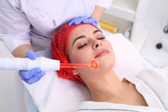 Receiving electric darsonval facial massage procedure.