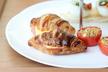Croissants with ham and cheese on white plate.