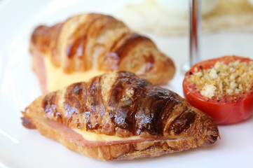 Croissants with ham and cheese on white plate.