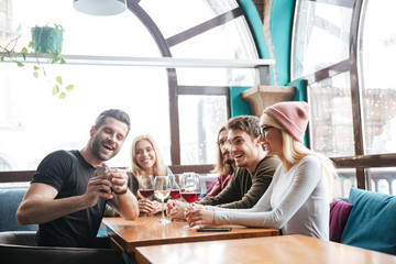 Smiling friends in cafe drinking alcohol and make a selfie.