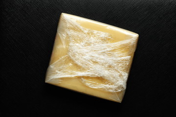 Cheese in thin transparent plastic sealed put on dark back ground scene represent the food and ingredient background concept related idea.