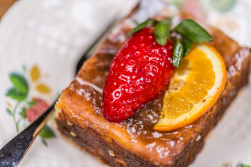 Piece of cake with pudding cream and ripe strawberry and lemon on a plate