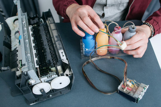 Repairman fixing CISS in office printer top view. Engineer refilling colorful cartridges. Equipment, business, cmyk, elektronik concept