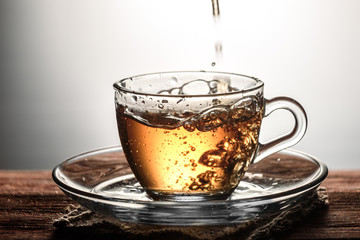 tea pouring into glass transparent Cup with bubbles on wooden table