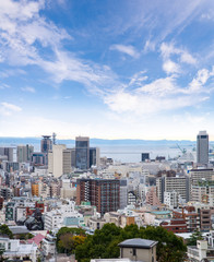 Fototapeta na wymiar Cityscapes of Kobe city with blue sky and fluffy tiny clouds, Skyline of Kobe, skyscraper office building and downtown of Kobe Bay, Japan, Kobe has been an important port city.