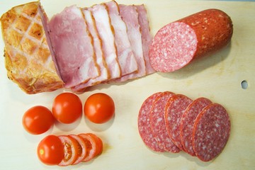 ham, salami, and tomatoes are on the Board.
