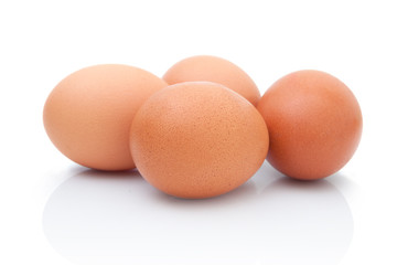 four brown chicken eggs isolated on white background with shadow reflection