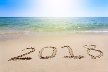 Year 2018 written at the sand beach with sea wave water