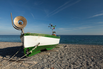 Fishing boat on beach over blue sky. Noli, Liguria, Italy.