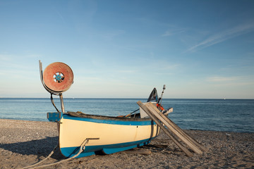 Fishing boat on beach over blue sky. Noli, Liguria, Italy.