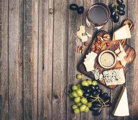 Grapes, red wine, cheeses, honey and nuts over rustic weathered wood. Top view with copy space.