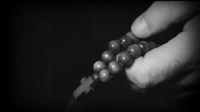 Praying hands with rosary cross. Macro shot.