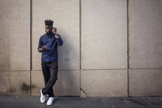 Young man with smartphone using earplugs