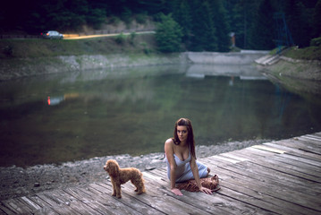 Woman with poodle dog at mountain lake.