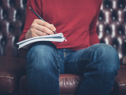 Man on sofa writing in notebook