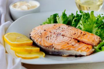 Baked salmon with lemon on white plate